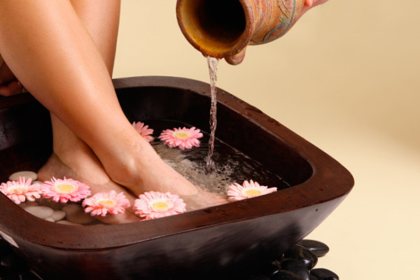 Water pouring from an earthenware pot into a luxurious aromatic foot soak