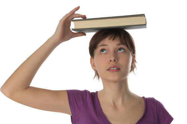 Красиво момиче студентът държи дебелата книга на главата