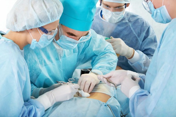 Portrait of four medical professionals performing an operation on woman