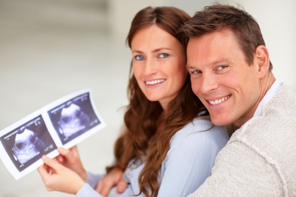 Portrait of a young couple holding a sonogram of their unborn child