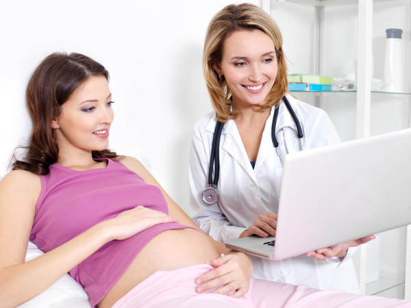 Pregnant woman and doctor with laptop