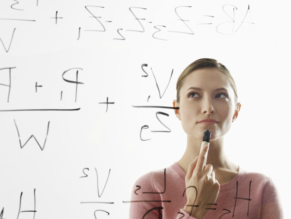 Young woman calculating equations on glass