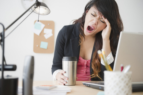 Pacific Islander businesswoman yawning at desk