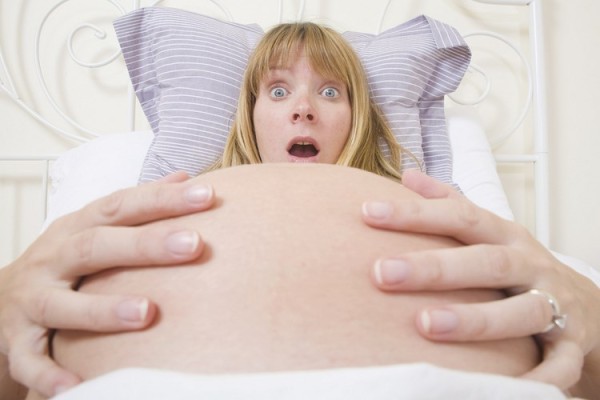 Бремена жена во кревет чувствува контракции.
