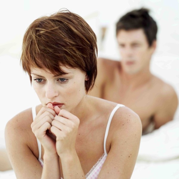 close-up of a woman sitting in a pensive mood with a man behind her