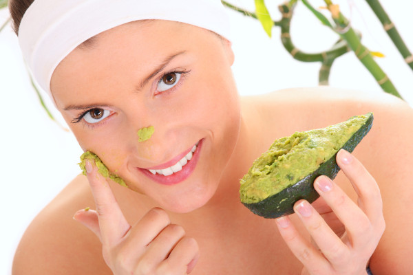 A portrait of a young woman applying natural avocado mask on her face