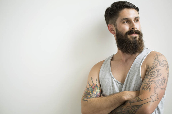 Bearded man with tattoos standing with arms crossed