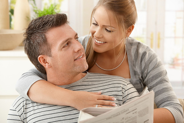 Happy couple sitting at home looking at each other, man holding