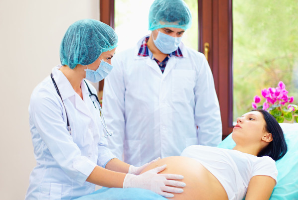 doctor palpates the abdomen of pregnant woman during childbirth