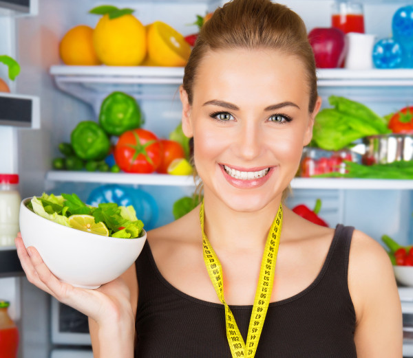 Портрет на слатка насмеана жена со лента за мерка и салата од свеж зеленчук, спортски тренер, концепт за органска храна, здравје и нега на убавина
