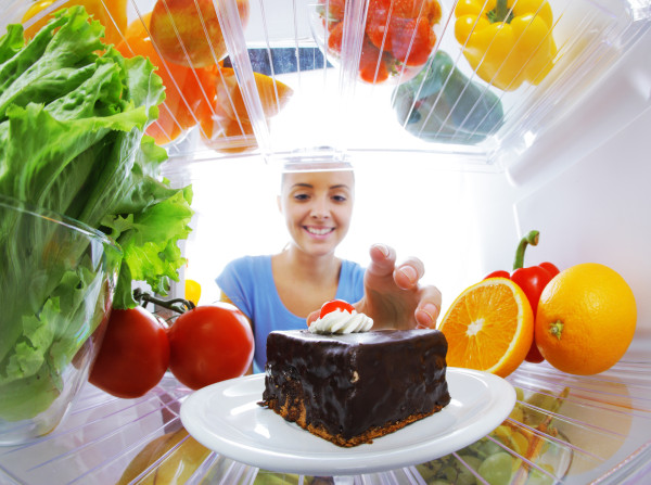 Young woman stops her diet and look for a cake in the refrigerator