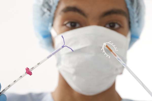 Young doctor holding two type of  IUD birth control copper coil device in hand, used for contraception