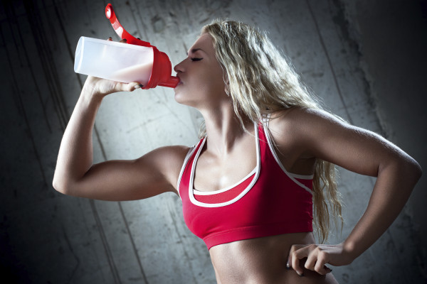Young muscular woman drinking sports nutrition.