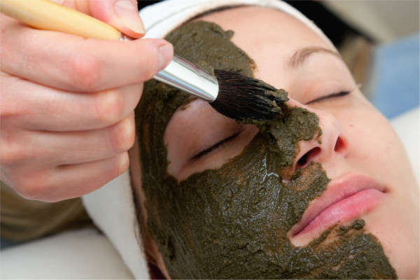 cosmetologist applying seaweed beauty mask