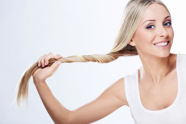 Beautiful young girl holding hair on a white background