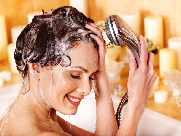 Woman washes her head at home bathroom.