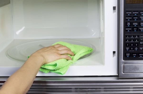16756896 - hand with microfiber cleaning rag wiping inside of microwave oven