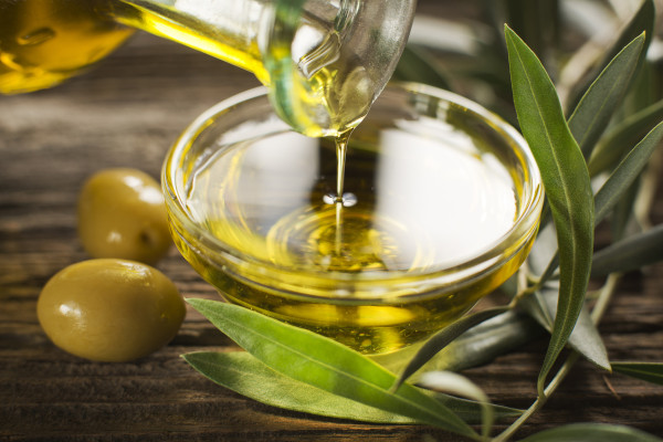 Шише истурено девствено маслиново масло во сад одблизу